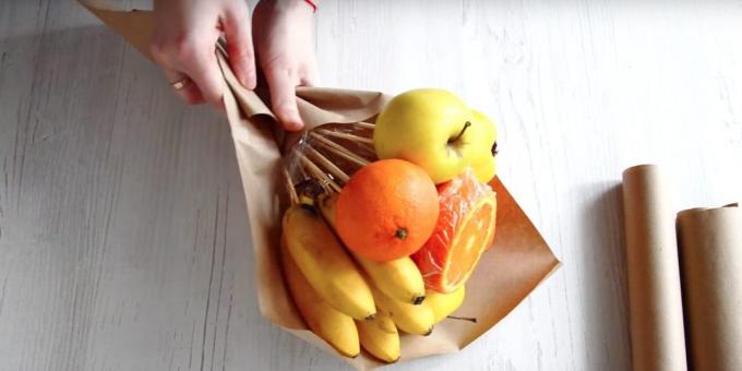 Pune-o grămadă de fructe cu mâinile în diagonală pe hârtie și înfășurați în partea de jos